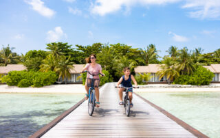 Exploring Maui with Kids: Mother and son riding their bikes on a walkway on an island