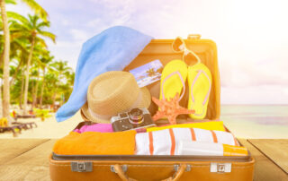 an opened suitcase with travel items for a beach vacation with a beach background
