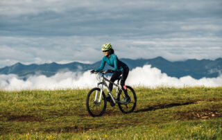 woman riding mountain bike on beautiful mountain top