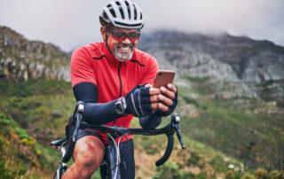Athletic man on a mountain bike using a smartphone on a bike trail