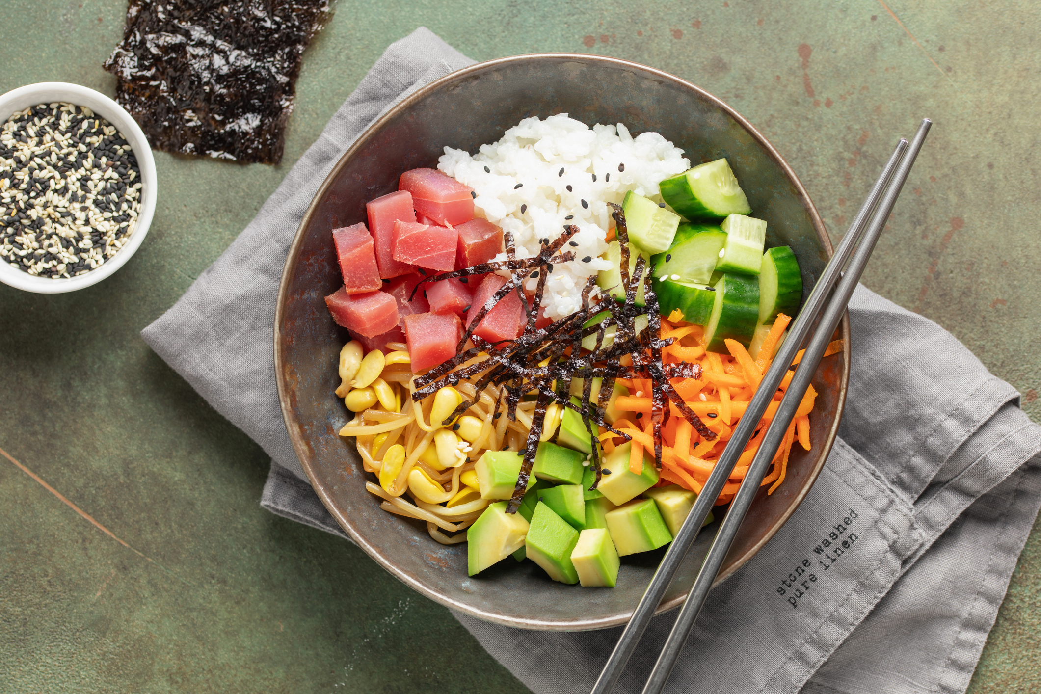 A traditional dish of Hawaiian cuisine. Poke bowl with tuna and vegetables in a bowl on the table.