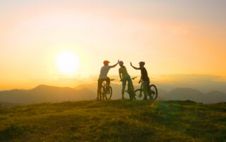 Mountain biking friends high five after reaching the scenic summit