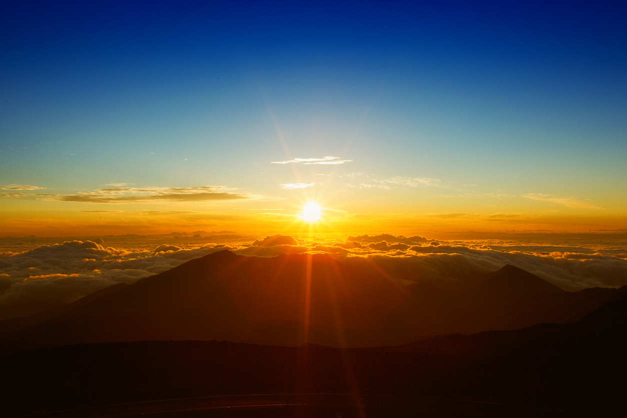 Sunrise over mountains with vivid orange sky and clouds.