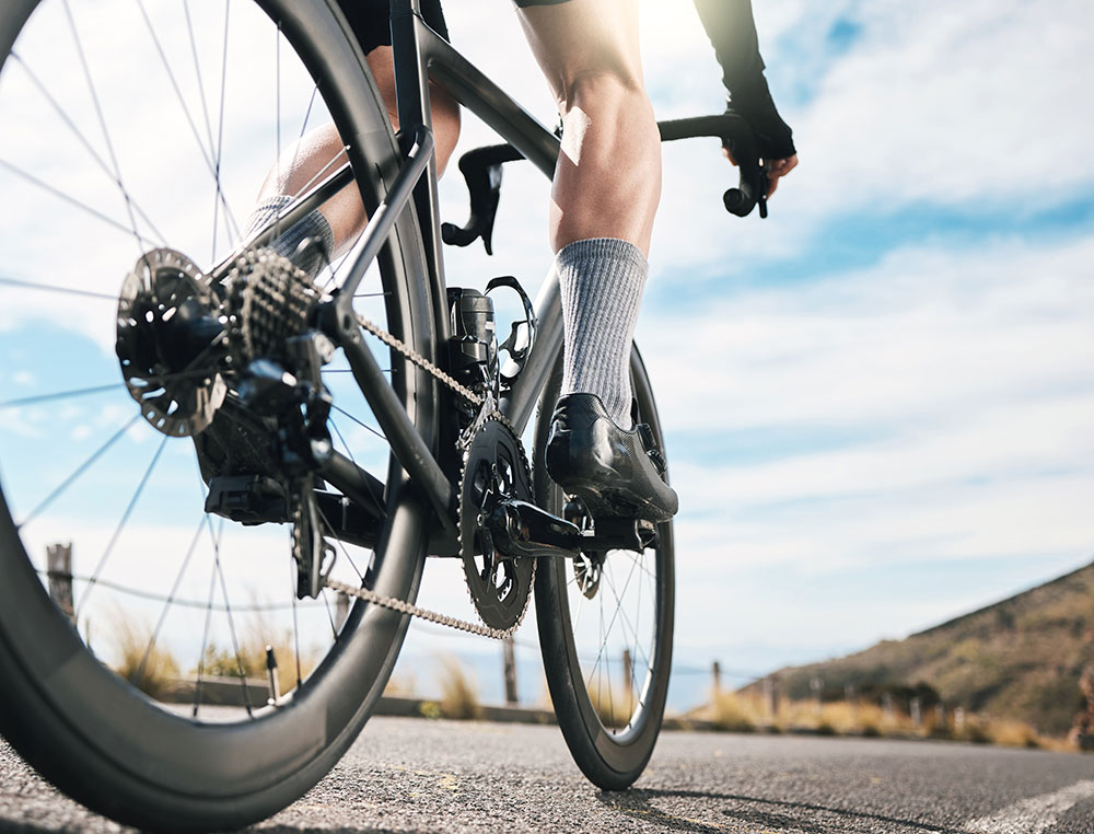 Cyclist in motion on a road bike under a blue sky.