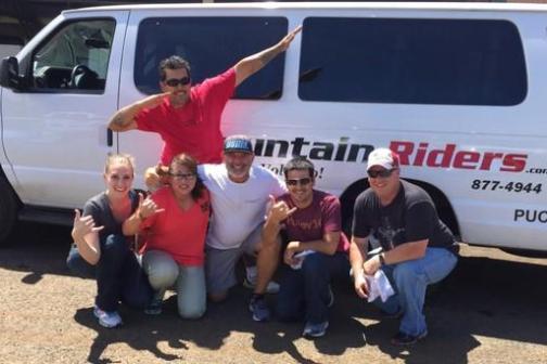 Group of six people in front of a white van with 'Mountain Riders' text.